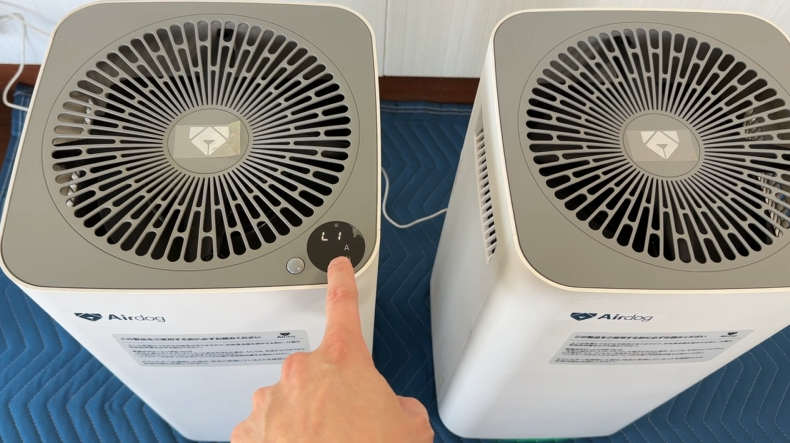 AirdogX5sの電源ボタンを指で操作して動作確認する様子