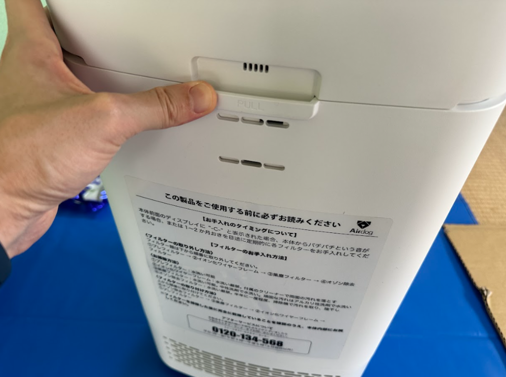 Airdog X5の背面カバーのプルタブを押している様子
